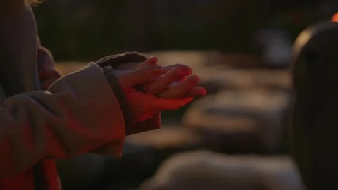 Close-up a woman's hands are heated near a heater at night outdoors Stock Footage 253165983