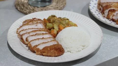 Close up woman's hands arranging deep fried pork chop into a plate with curry an Stock Footage 252166229