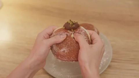 Close-up of woman’s hands breaking doughnut with Dubai chocolate filling Stock Footage 321020031