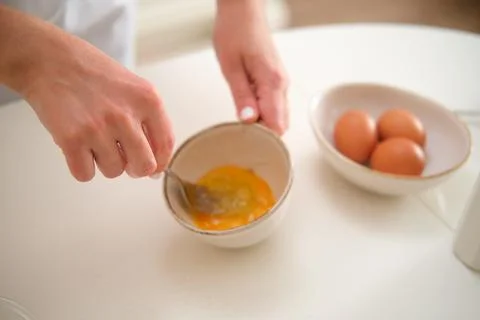 Close up of a woman's hands breaking eggs in the kitchen. Process of cookin.. Stock Photos
