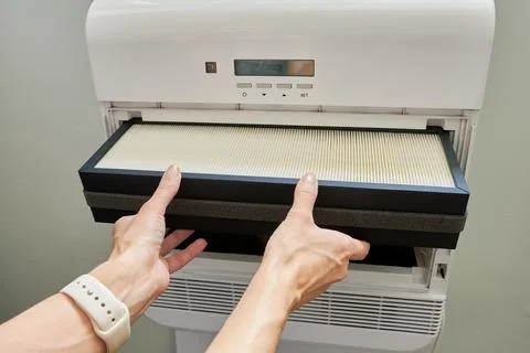 Close-up of a woman's hands changing the filter in an air conditioner. Stock Photos