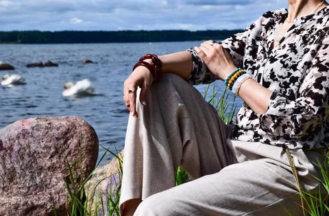 Close-up of a woman's hands clasped over her knee outdoors by the water 库存照片