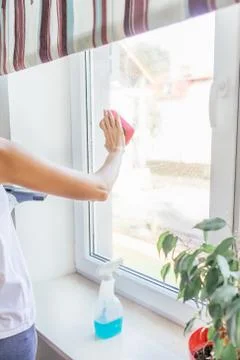 Close up of woman's hands cleaning window glass with sponge. Housework concept. Stock Photos