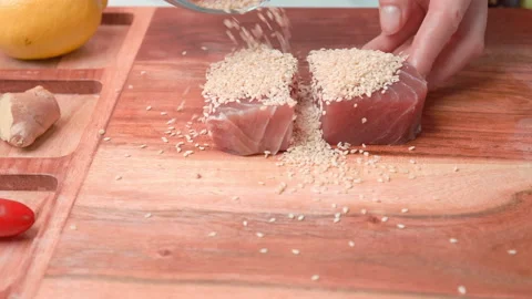 Close-up of woman's hands Coating raw tuna in sesame seeds in 4K. Stock Footage 141302408