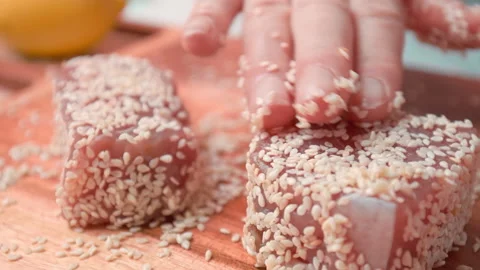Close-up of woman's hands Coating raw tuna in sesame seeds in 4K. Stock Footage 141302666
