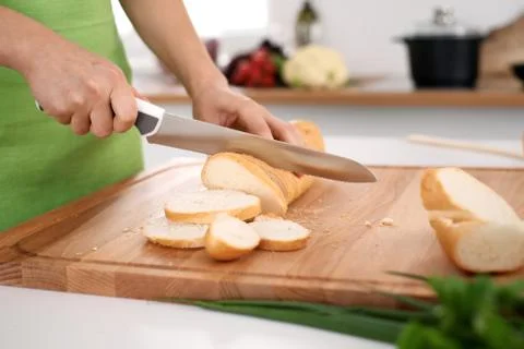 Close up of woman's hands cooking in the kitchen. Housewife slicing white bread 库存照片