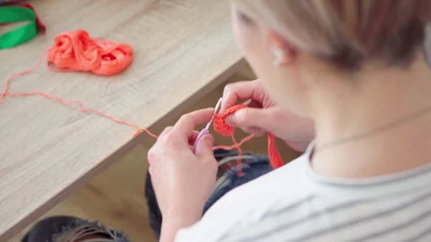 Close-up of woman's hands crocheting doll clothes using a hook and yarn. Creativ Stockbeeldmateriaal 333796869