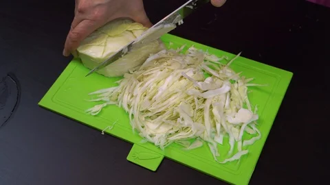 Close-up of woman's hands cutting cabbage in kitchen Stock Footage 99044477