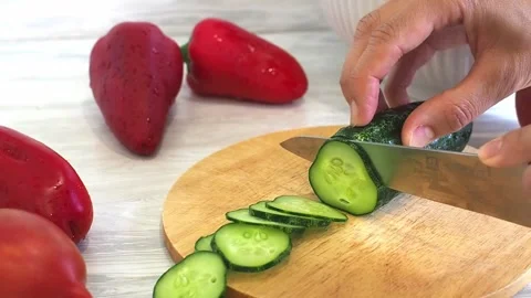 Close-up of woman's hands cutting cucumber on cuting board in the kitchen Stock Footage 248520363