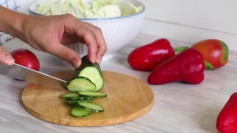 Close-up of woman's hands cutting cucumber on cuting board in the kitchen Stock Footage 248520396