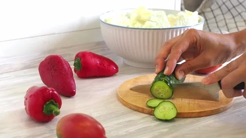 Close-up of woman's hands cutting cucumber on cuting board in the kitchen Stock Footage 248638188
