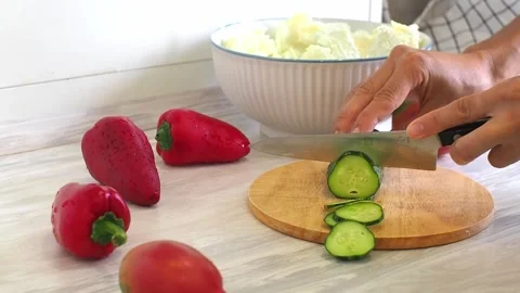 Close-up of woman's hands cutting cucumber on cuting board in the kitchen Stock Footage 248760730