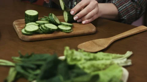 Close up of woman`s hands cutting cucumbers into rings at the table with all Stock Footage 61679967
