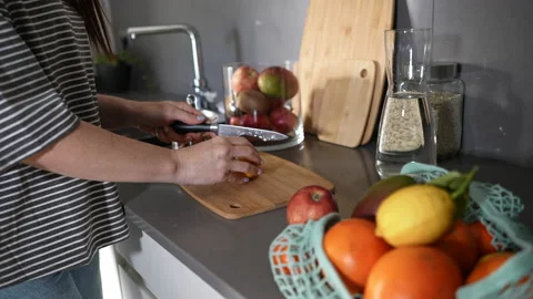 Close up of woman's hands cutting a lemon on a wooden cutting board preparing Stock Footage 169774576