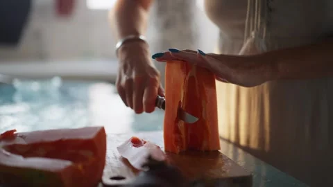 Close up of woman's hands cutting papaya fruit, pawpaw fruit in half using a Stock Footage 302371943