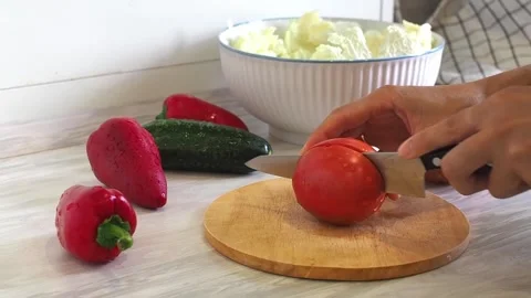 Close-up of woman's hands cutting tomato on cuting board in the kitchen Video stock 248520266