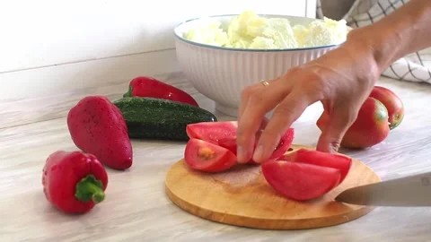 Close-up of woman's hands cutting tomato on cuting board in the kitchen Stock Footage 248520299