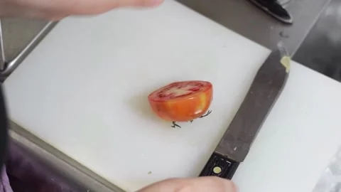 Close-up of a woman's hands cutting a tomato in half, then grabbing the gra.. Stock Footage 248729280