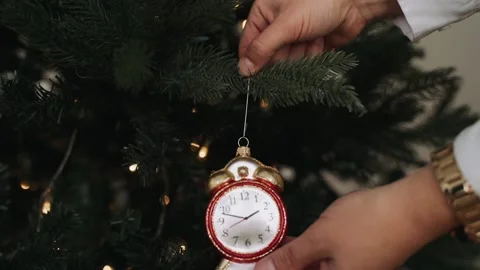 Close-up of woman's hands decorating Christmas tree wist antique clock toy Stock Footage 164064436