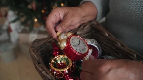 Close-up of woman's hands decorating Christmas tree wist antique clock toy Stock Footage 166544740