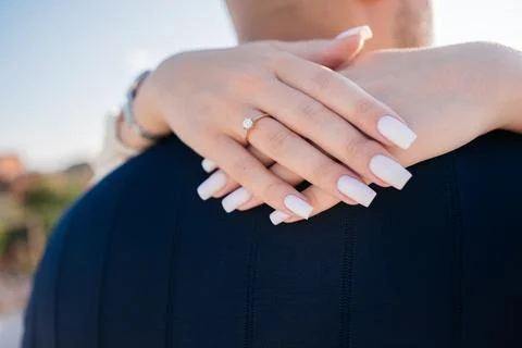 Close up of a woman's hands with a diamond ring embracing her partner 写真素材