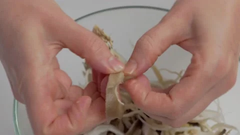 Close-up of a woman's hands dividing fresh mushrooms into fibers and throwing Stock Footage 169756377