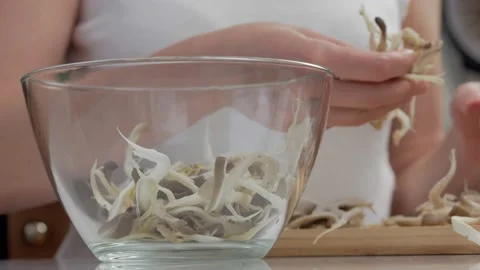 Close-up of a woman's hands dividing fresh mushrooms into fibers and throwing Stock Footage 169875028