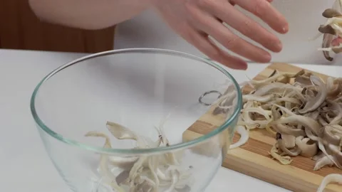 Close-up of a woman's hands dividing fresh mushrooms into fibers and throwing Stock Footage 171068556