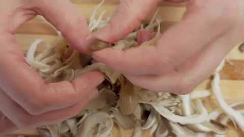 Close-up of a woman's hands dividing fresh mushrooms into fibers and throwing Stock Footage 171342646
