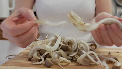 Close-up of a woman's hands dividing fresh mushrooms into fibers and throwing Stock Footage 171417174