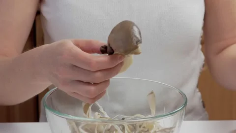 Close-up of a woman's hands dividing fresh mushrooms into fibers and throwing Stock Footage 171765848