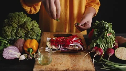 Close up of a woman's hands dropping herbs on a salad plate, surrounded by ra Stock Footage 145242111