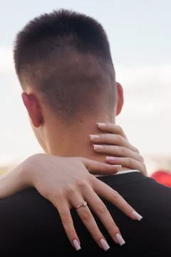 Close up of womans hands with engagement ring hugging man from behind showi.. Stock Photos