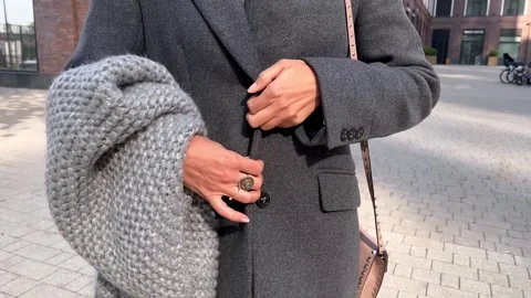 Close up of woman's hands fastening button on gray jacket, bundling up and Stock Footage 251812499