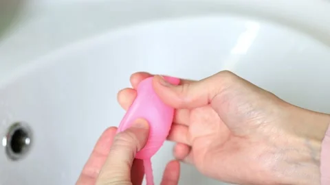 Close-up of a woman's hands folding a menstrual cup showing how to use it Stock Footage