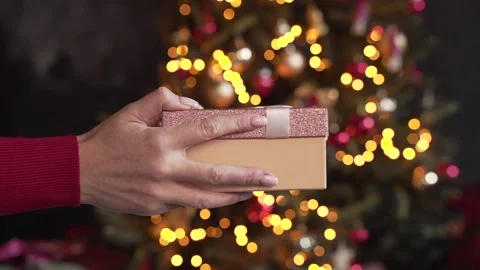 Close up of woman's hands give a gift near the Christmas tree Stock Footage 221465346