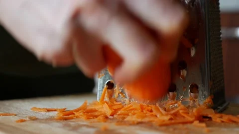 Close-up of a woman's hands grates carrots on a grater. Housewife grates carrot Stock Footage 165452976
