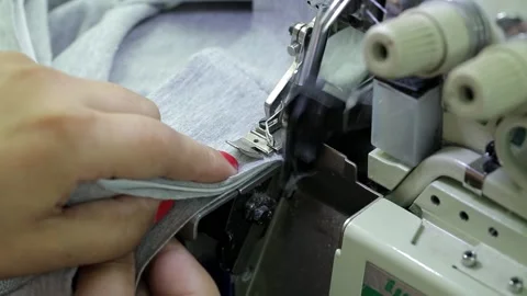 Close-up of a woman's hands handling fabric on an overlock machine. Vídeos de archivo 136076902