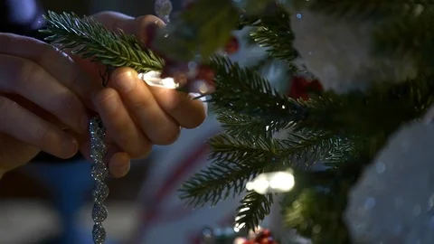 Close up of a woman's hands hanging an icicle on a Christmas tree. Stock Footage 100649336