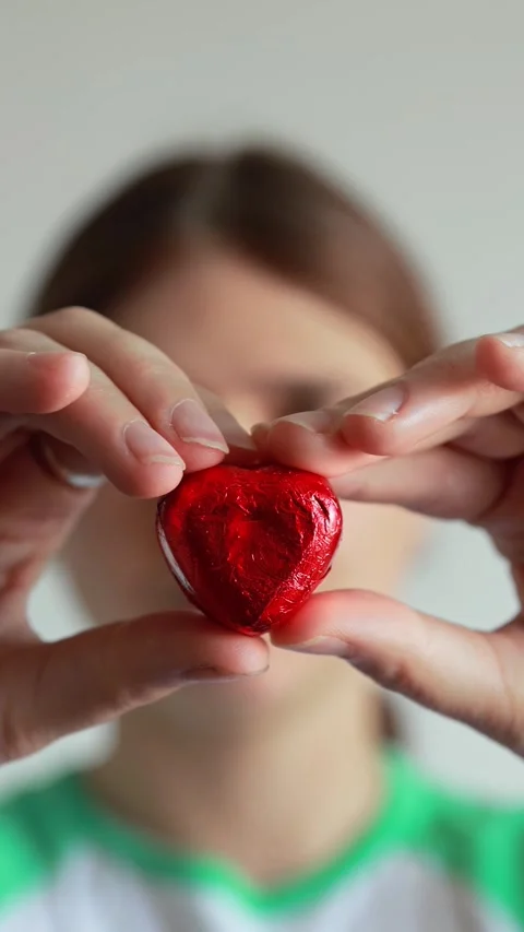 Close-up of a woman's hands holding a red heart-shaped candy or chocolate w.. Stock Footage 341562534