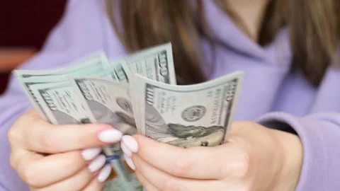 Close-up of a woman's hands holding a stack of 100 dollar bills. a woman counts Stock Footage 193646407