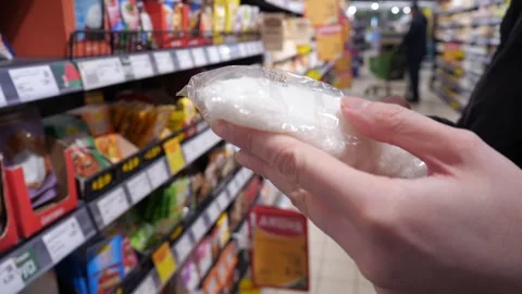 Close-up of womans hands holding a transparent bag of sugar, salt or other food Stock Footage 314258256