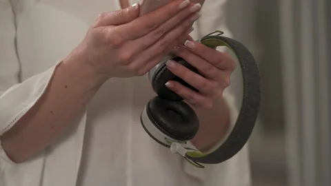 A close-up of a woman's hands holding wireless headphones and smartphone. Stock Footage 104901360