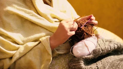 Close-up of a woman's hands knitting a wool scarf. A lady sews from thick yarn. Stock Footage 262568346