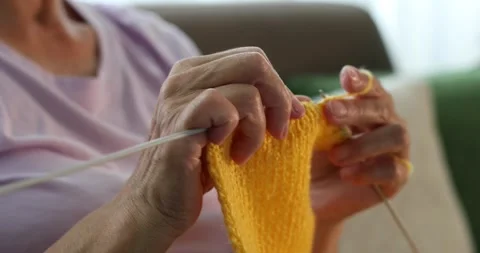 Close up of woman's hands knitting with a yellow wool Stock Footage 278149048