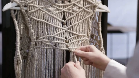 Close up of a woman's hands knotting a boho macrame vest Stock Footage 127039950