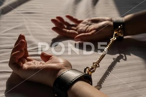 Close-up of woman's hands in leather handcuffs. Sex toy ...