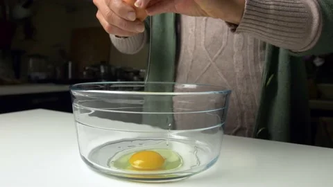 Close up woman's hands open eggs in glass bowl for sweet preparation. 库存影片 219775403