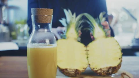 Close up of woman's hands opening a sliced pineapple with bottle of fresh Stock Footage 273510612