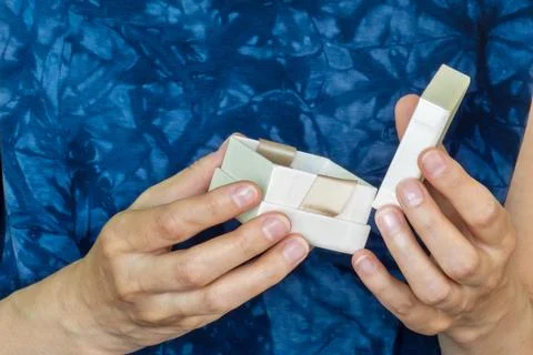 Close-up of woman's hands opening small elegant gift box on blue background Stock Photos